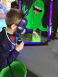 boy in Halloween costume wearing a purple mask touching green slime