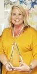 smiling woman in yellow shirt holding triangular acrylic award