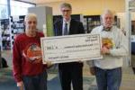 three men holding oversized check