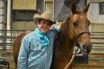 male student wearing cowboy hat with his arm draped across his horse