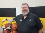 Darren Bizarri leaning on cage of basketballs