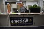 woman standing behind a desk with a welcome sign