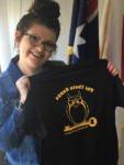 smiling student holding up a Phi Theta Kappa t-shirt