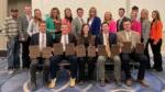 5 people seated with awards and 13 people standing