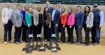 15 people standing with awards on the ground