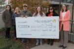 6 people standing outdoors holding oversized check